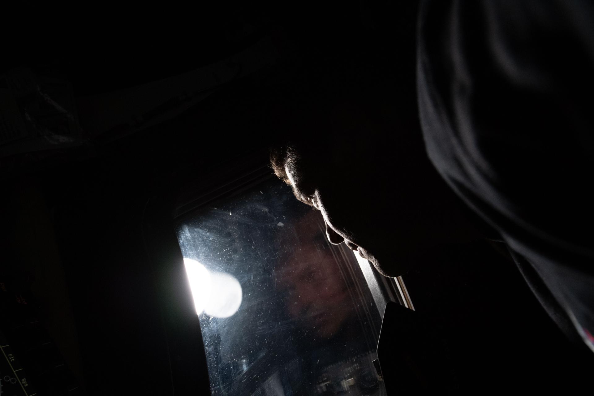 An Artemis II crew member reflected in a spacecraft window during the lunar flyby